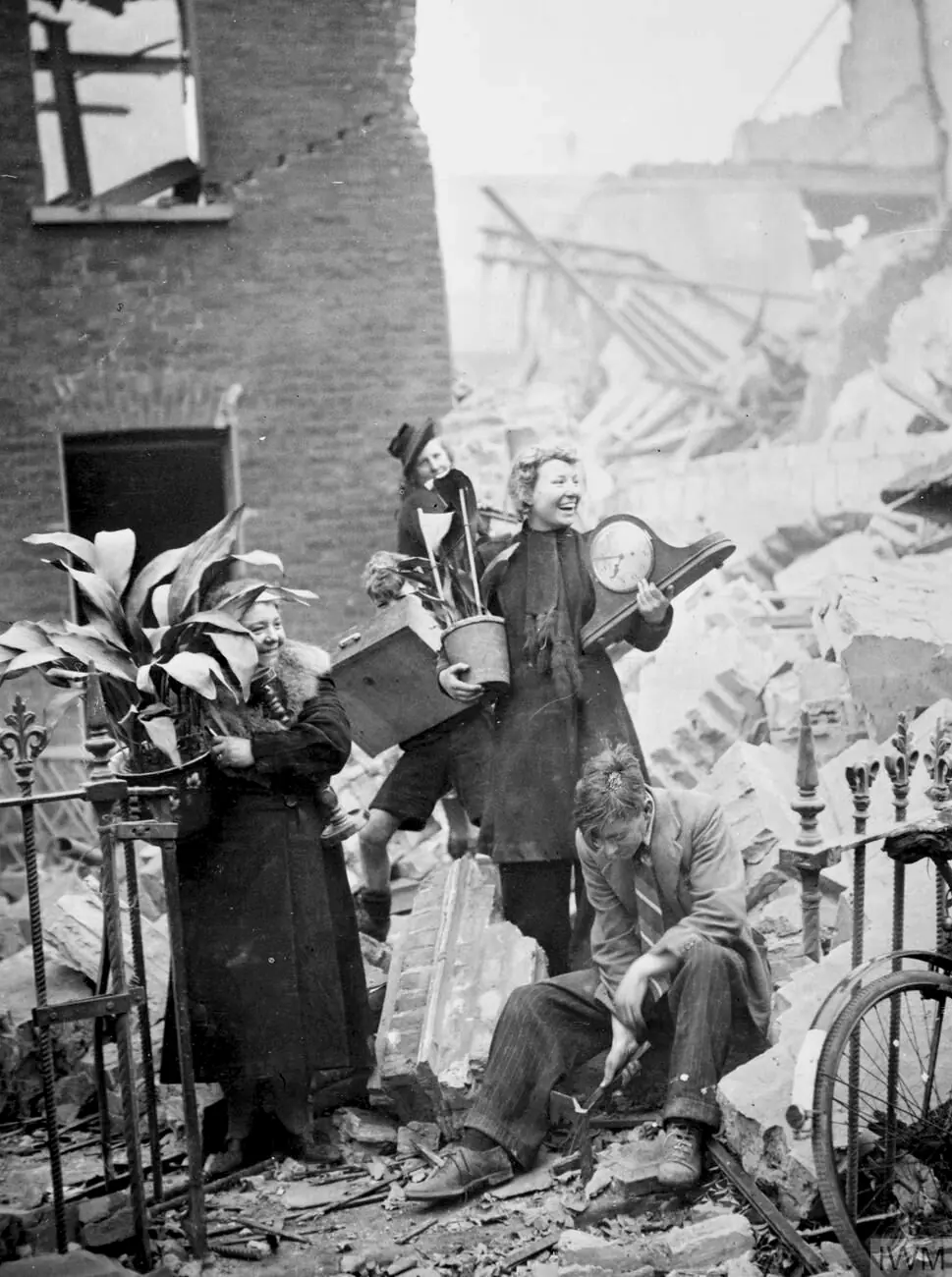 Two women salvaging potted plants and a clock from their bombed house